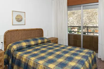 a bedroom with a bed with a blue and yellow blanket at Florazar 2, Ii-14-A in Cullera