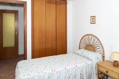 a bedroom with a bed and a wooden cabinet at Florazar 2, Vi-1-C in Cullera