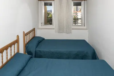 two beds with blue sheets in a bedroom with two windows at Florazar 2, Vi-5-B in Cullera