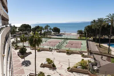 a view of a tennis court with palm trees and the ocean at Florazar 2, Vi-5-B in Cullera