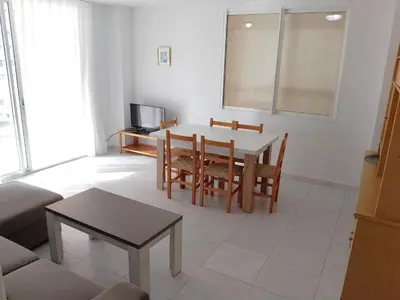 a living room with a table and chairs and a television at Florazar 3, 3-C in Cullera