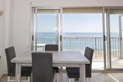 a dining table and chairs with a view of the ocean at Frontalmar, Esc-A, 8º-29 in Cullera