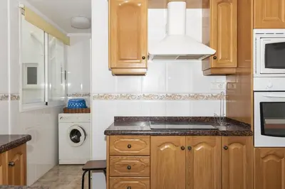 a kitchen with wooden cabinets and a washer and dryer at Frontalmar, Esc-A, 8º-29 in Cullera