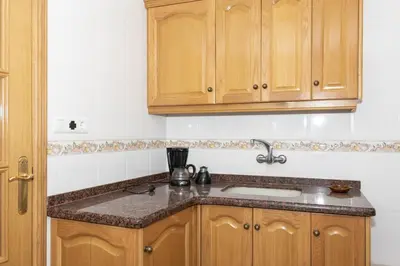a kitchen with wooden cabinets and a sink at Frontalmar, Esc-A, 8º-29 in Cullera