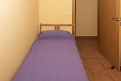 a small bed in a small room with purple sheets at Frontalmar, Esc-B, 8º-32 in Cullera