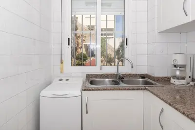 a white kitchen with a sink and a window at Hawai Bajo in Faro de Cullera