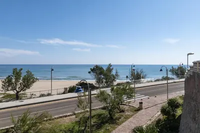 a road next to a beach with the ocean at Hawai Bajo in Faro de Cullera