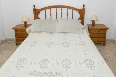 a bed with a white bedspread and two night stands at Lider, 2-I in Cullera