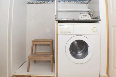 a laundry room with a washing machine and a stool at Lider, 44-E (Planta Baja) in Cullera
