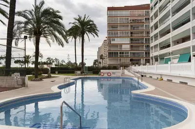 a large swimming pool with palm trees and buildings at Lider, 4-D in Cullera