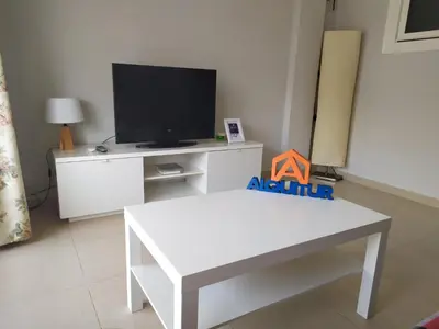 a living room with a tv and a white table at Mar Y Montaña 7º-119 in Cullera