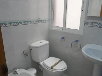 a white bathroom with a toilet and a sink at Nautilo, 8º-15 in Cullera