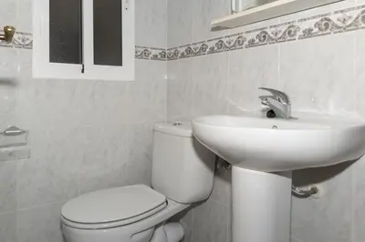 a white bathroom with a toilet and a sink at Nautilo, 8º-15 in Cullera