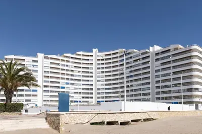 a large white building with a palm tree in front of it at Prado, B-6º-64 in Cullera