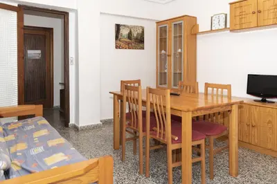 a dining room with a wooden table and chairs at Provence, 5º-17 in Cullera