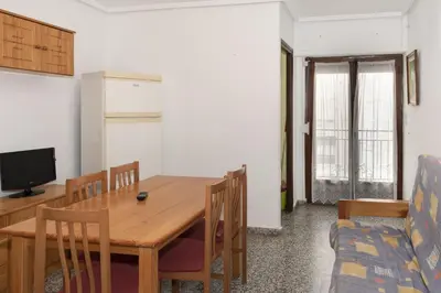 a dining room with a wooden table and a couch at Provence, 5º-17 in Cullera