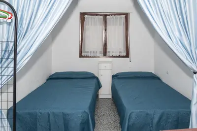two beds in a room with blue sheets and a window at Provence, 7º-25 in Cullera