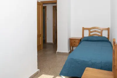a bedroom with a bed and a wooden chair at Santa Marta, Iii-A 7º-16 in Cullera