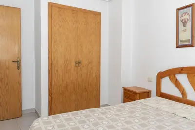 a bedroom with a bed and a wooden cabinet at Seniades, 6º-16 in Cullera