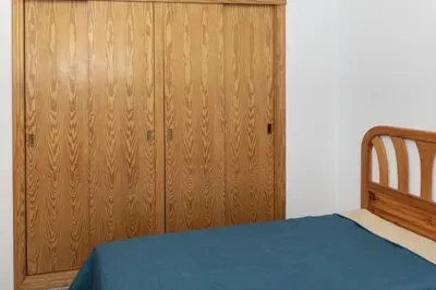 a bedroom with a bed and a wooden cabinet at Villas Cap Blanc, 1-31 Cab I-36 in Cullera