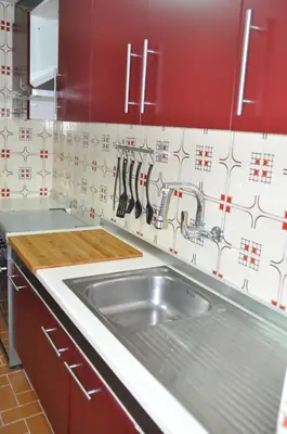a kitchen with a stainless steel sink and red cabinets at Palm Tree Cullera in Cullera