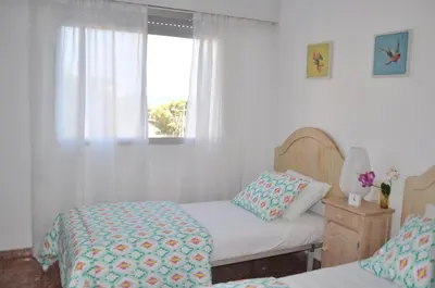 a bedroom with two beds and a window at Palm Tree Cullera in Cullera