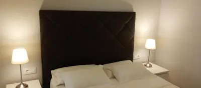 a bedroom with a black headboard and two lamps at Apartamentos BARRACA in Valencia