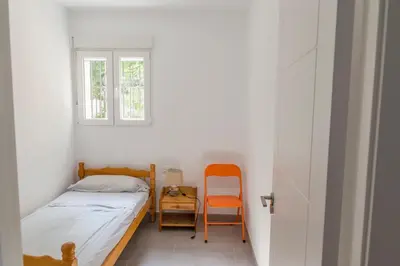 a small bedroom with a bed and a chair at Apartamento cerca de la Playa y el Centro in Valencia