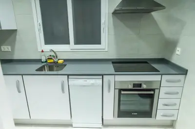 a white kitchen with a sink and a stove at Apartamento cerca de la Playa y el Centro in Valencia