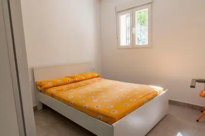 a bedroom with a bed with an orange comforter and a window at Apartamento cerca de la Playa y el Centro in Valencia