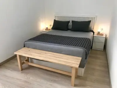 a bedroom with a bed and a wooden bench at Teixidors de Palomar - PalomarGroup in Valencia