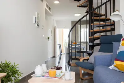 a living room with a blue couch and a spiral staircase at SingularStays Puzol Beach VI in Puzol