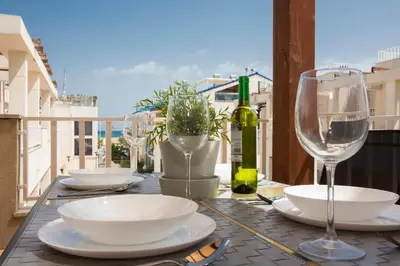 a table with plates and wine glasses on a balcony at SingularStays Puzol Beach VI in Puzol