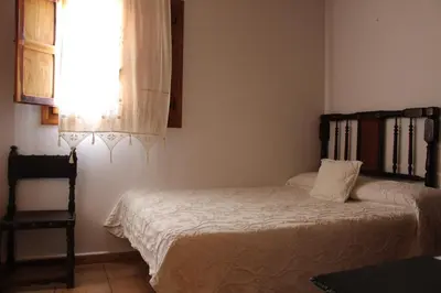 a bedroom with a bed and a chair and a window at Hotel La Villa in Requena