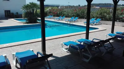 a swimming pool with blue lounge chairs next to it at Hotel La Carreta in Chiva