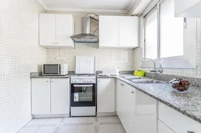 a white kitchen with white cabinets and a sink at Casa Victoria in Valencia