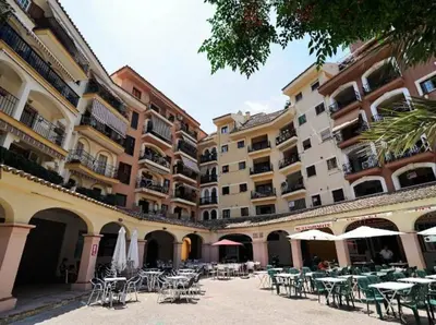 a courtyard with tables and chairs in front of a building at Apartment in Little Venice in Port Saplaya
