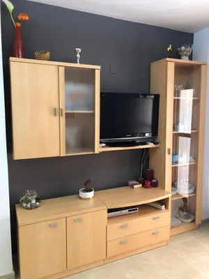 a entertainment center with a flat screen tv and a cabinet at Apartamento junto al mar Los Marineros con acceso independiente por terraza in Puzol