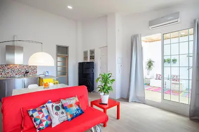 a living room with a red couch and a kitchen at Atico Valencia Sorolla in Valencia