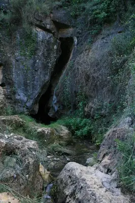 a cave in the side of a mountain with a creek at Casa La Chelva in Alcudia de Veo