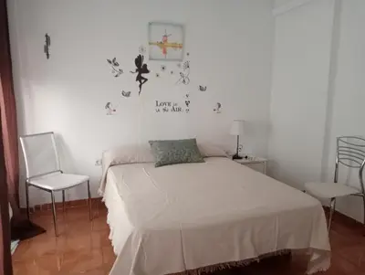 a white bedroom with a bed and two chairs at Apartamento La Marina Real in Valencia