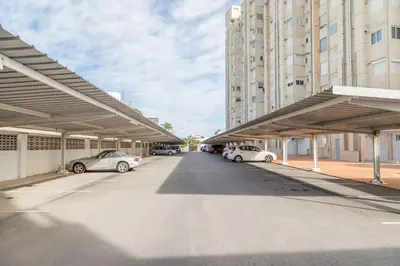 a parking lot with cars parked in front of tall buildings at Apartamento Calipso in El Palmar