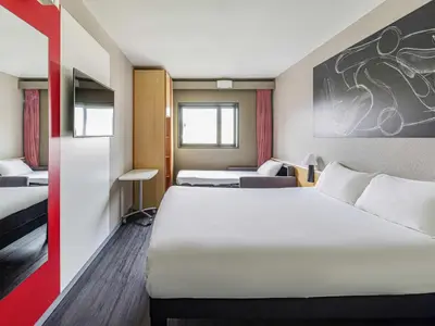 a hotel room with two beds and a tv at Ibis Valencia Bonaire Aeropuerto in Aldaya