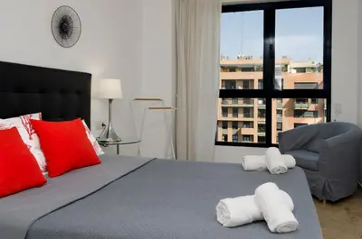 a bedroom with a bed with red pillows and a chair at ApartUP Francia Views in Valencia