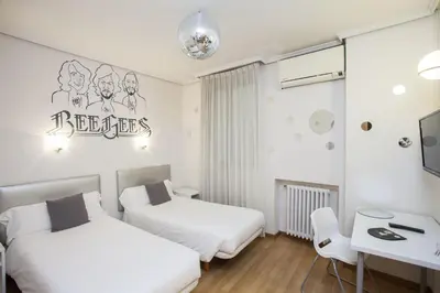 a bedroom with two beds and a desk and a table at Hotel Valencia de la Música in Valencia