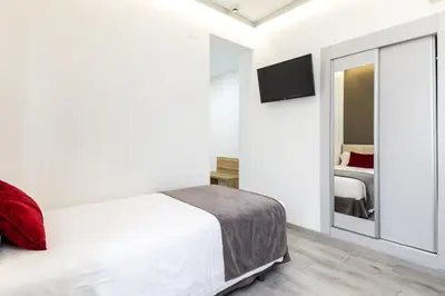 a white bedroom with a bed and a mirror at Sweet Hotel Renasa in Valencia