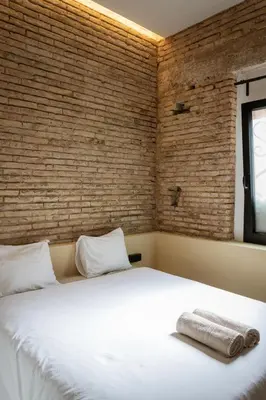 a bedroom with a large white bed with a brick wall at Beach loft in Valencia