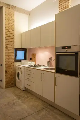 a kitchen with white cabinets and a washer and dryer at Beach loft in Valencia
