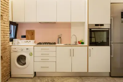 a kitchen with white cabinets and a washer and dryer at Beach loft in Valencia