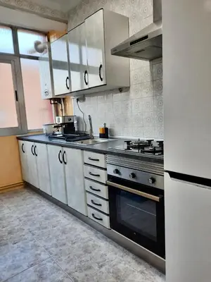 a kitchen with white cabinets and a stove top oven at Piso en la playa in Valencia